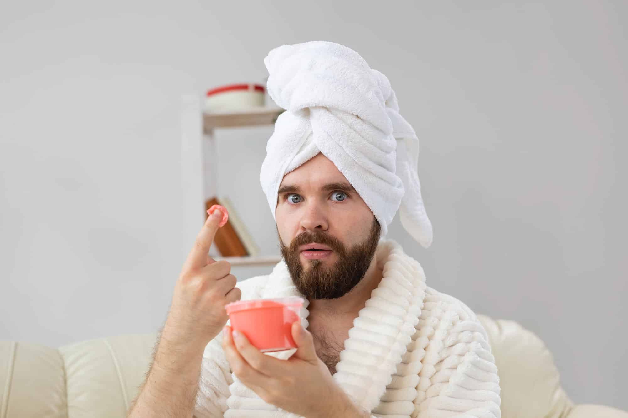 Handsome man holding cosmetic pink scrub for skin. Spa, body and skin care for man concept